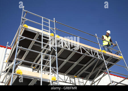 Ein Arbeiter steht ein großes Gerüst Arbeitsbühne mit einer Aluminium-Tower-System erstellt. Stockfoto