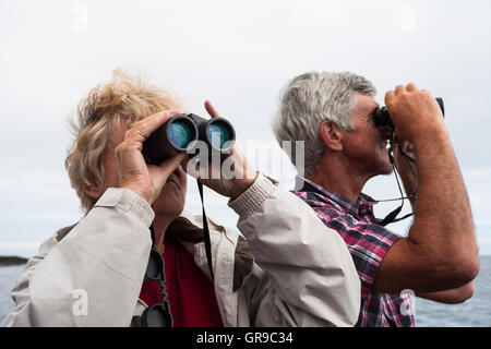 Erwachsenes paar, 60-65 Jahre, mit Fernglas, Northumberland, England, Vereinigtes Königreich Stockfoto