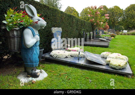 Das Grab eines Kindes mit einer Statue eines Kaninchens mit Blumen drin Stockfoto