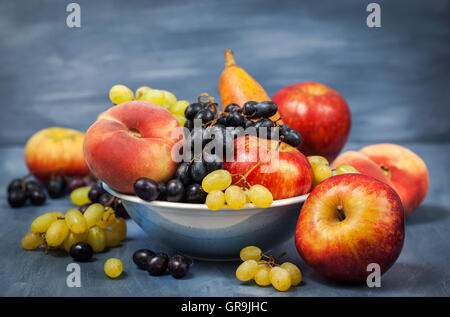 Frische reife herbstliche Früchte - Pfirsiche, Birnen, Äpfel und Trauben Stockfoto