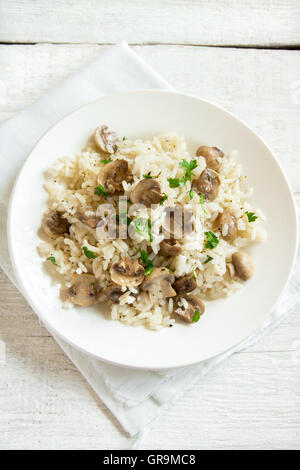 Pilz-Risotto mit Petersilie auf weißem Holz Hintergrund Stockfoto