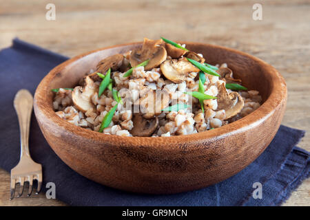 Russische traditionelle Buchweizen mit Champignons und Schnittlauch in Holzschale Stockfoto