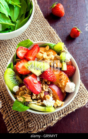 Frischer Obstsalat mit Müsli, Feta-Käse und Honig in Schale für gesundes Frühstück Stockfoto