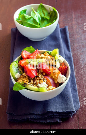 Frischer Obstsalat mit Müsli, Feta-Käse und Honig in Schale für gesundes Frühstück Stockfoto