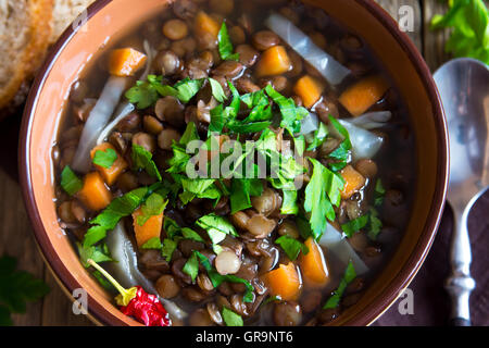 Vegetarische Linsensuppe (Eintopf) mit Gemüse und Petersilie auf rustikalen hölzernen Hintergrund Stockfoto