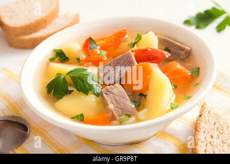 Fleisch und Gemüse Suppe mit Petersilie in einer Schüssel über weißem Holz Hintergrund hautnah Stockfoto