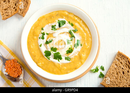 Creme von Linsensuppe mit Frischkäse und Petersilie in einer Schüssel über rustikale Holz Hintergrund Stockfoto