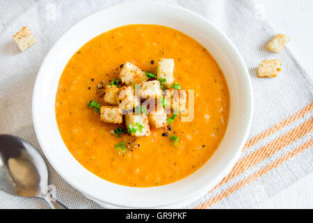 Tomaten und Karotten Gemüsesuppe mit Croutons, Grüns und Gewürzen in weiße Schüssel hautnah Stockfoto