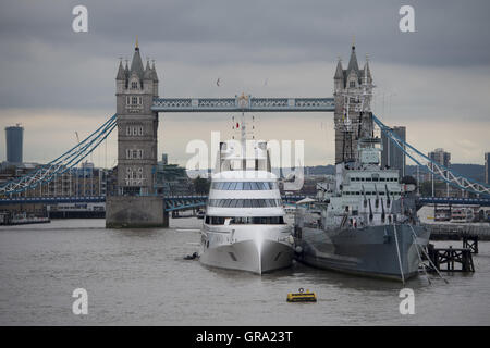 Ein 390ft Motoryacht Zugehörigkeit zu russischen Tycoon Andrey Melnichenko neben HMS Belfast (rechts) auf der Themse in London. Stockfoto