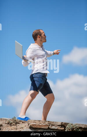 junger Mann wirft einen laptop Stockfoto