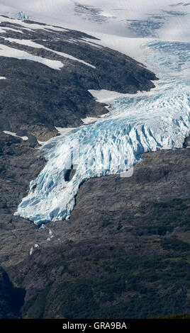 Ein Gletscher hängt hartnäckig an einem felsigen Berghang. Stockfoto