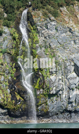 Eine schmale Wasserfälle Kaskaden hinunter in die Bucht eine Felswand. Stockfoto