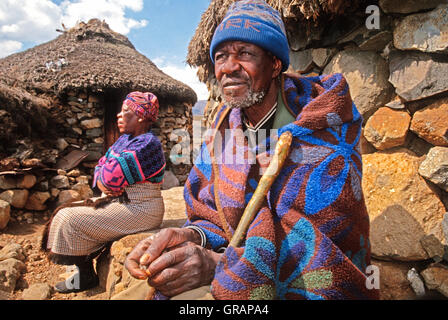 Älteres Ehepaar der Basotho durch ihre Rundhütten in Sani Pass in Lesotho Stockfoto