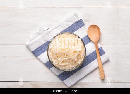 Draufsicht des Sauerkrauts in Glasschüssel auf weißer Holztisch Stockfoto