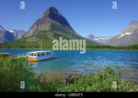 Ausflugsschiff im Dock Masny Glacier Lodge. Grinnell Point ist im Hintergrund, über den See. Glacier Nationalpark, Mont Stockfoto