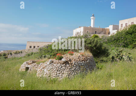 Trulli gefallenen in den Ruin, grüne Wiese, im Hintergrund Leuchtturm, Meer, blauer Himmel weiße Wolken, Apulien, Italien Stockfoto