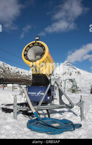 Inaktive gelb Schneekanone gegen blauen Himmel im Hintergrund Schnee bedeckt Berge Stockfoto