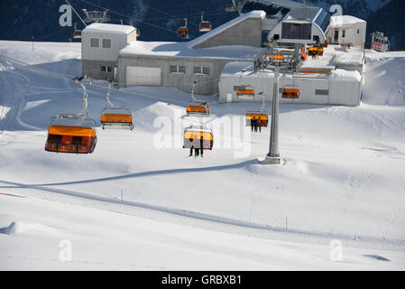 Sesselbahn mit Orangen Wetterschutzhauben an einem sonnigen Wintertag, Midwaystation Stockfoto