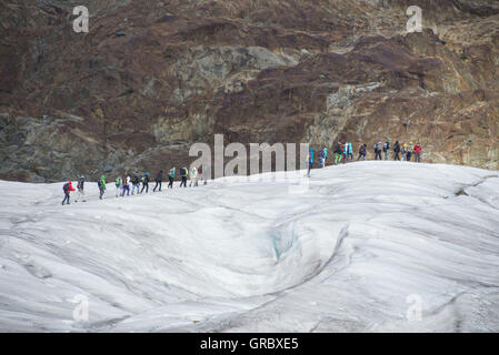 Eine Gruppe von Menschen geht auf dem Aletschgletscher Stockfoto