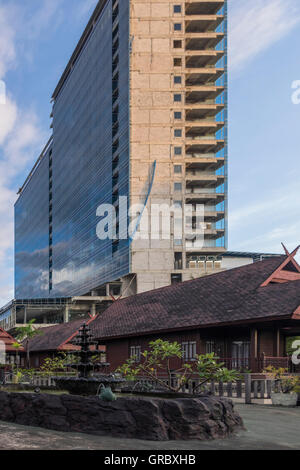 Extreme In den traditionellen Holzhäusern der Vordergrund In den Hintergrund unvollendete Hochhaus. Makassar, Southsulawesi, Indonesien. Stockfoto