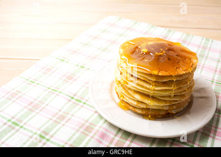 Stapel von Frühstück Pfannkuchen mit Honig auf den weißen Teller.  Hausgemachte Pfannkuchen zum Frühstück serviert. Kopieren Sie Raum. Stockfoto