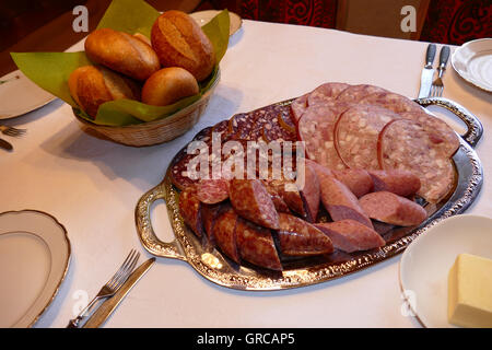 Hausgemachte Wurst Teller und Brötchen am gedeckten Tisch Stockfoto