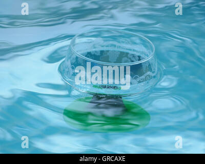 Leere Glas Wein schwimmt auf der Wasseroberfläche aus einem Pool, Pool-Party Stockfoto