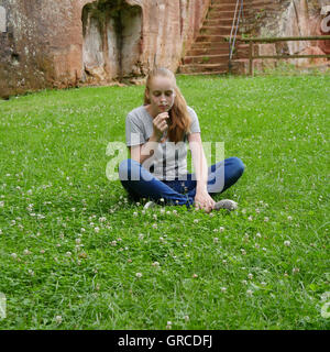 Teenager, junge Mädchen sitzt im Schneidersitz auf einer Blumenwiese Stockfoto