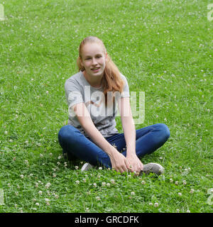 Teenager, junge Mädchen sitzt im Schneidersitz auf einer Blumenwiese Stockfoto