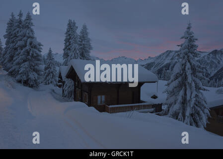 Landschaft und Pfad, bedeckt tief Schnee, mit Tannen und Chalets, in der Morgendämmerung Stockfoto