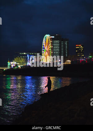 Ein Fischer in der Nacht In Köln vor dem Hintergrund der Kirmes Stockfoto