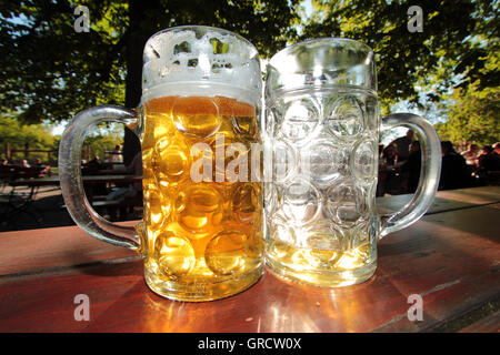 Volle und leere Biergläser am Nachmittag Sonne am Münchner Biergarten Hirschgarten Stockfoto