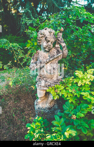 Steinstatue von einem Cherub Geigenspiel in einem Garten Stockfoto