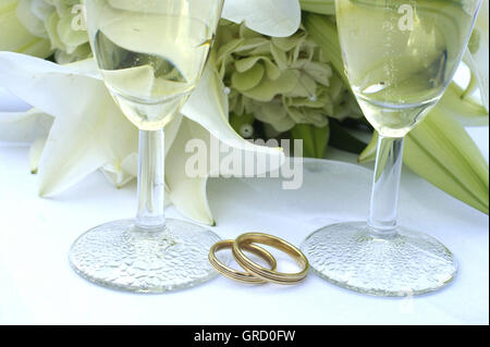 Symbol Hochzeit, Trauringe, zwei Gläser Sekt und Brautstrauß Stockfoto