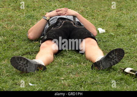 Betrunkener Mann In Lederhose schlafen auf dem Oktoberfest Stockfoto