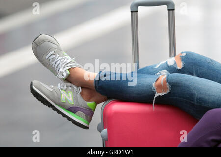 Junge Frau ihre Beine auf einen Koffer am Central Railway Station Frankfurt ruht Stockfoto