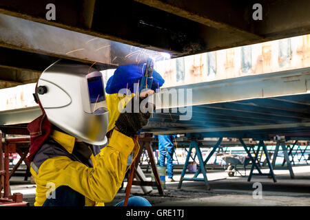 Arbeiter reparieren die Schäden Unterseite der Container, Industrie, Fabrik, Schweißen closeup Stockfoto