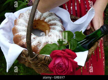 Korb, gefüllt mit einem Kuchen, Wein und eine rote Rose, wie Little Red Riding Hood Stockfoto