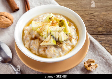Frische Haferflocken Brei mit Äpfel, Honig, Nüssen und Zimt hautnah auf rustikalen hölzernen Hintergrund Stockfoto