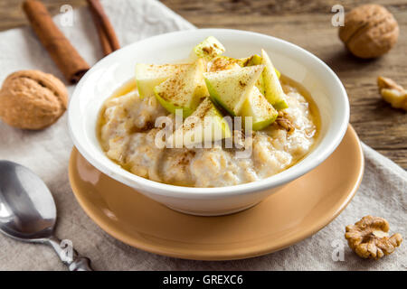 Frische Haferflocken Brei mit Äpfel, Honig, Nüssen und Zimt Nahaufnahme auf rustikalen hölzernen Hintergrund für gesundes Frühstück Stockfoto