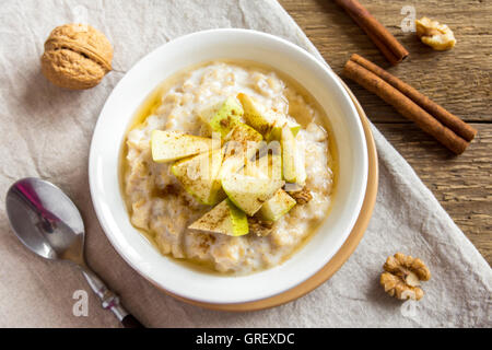 Frische Haferflocken Brei mit Äpfel, Honig, Nüssen und Zimt Nahaufnahme für gesundes Frühstück Stockfoto