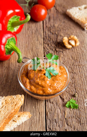 geröstete Paprika-Dip mit Nüssen und Brot im Glasschüssel über rustikalen hölzernen Hintergrund closeup Stockfoto