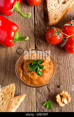 geröstete Paprika-Dip mit Nüssen und Brot im Glasschüssel über rustikalen hölzernen Hintergrund closeup Stockfoto