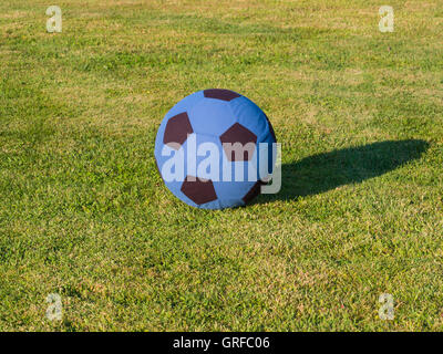 big blue and black soft soccer ball on the grass of a field Stockfoto