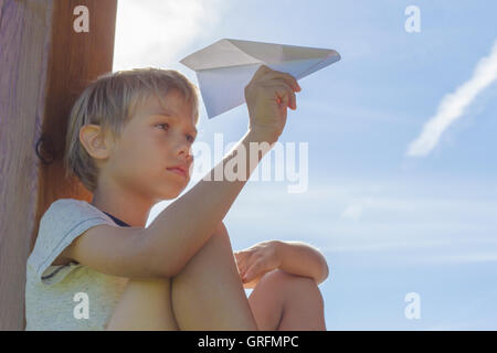 Junge, ein Papierflugzeug gegen blauen Himmel fliegen. Sommertag. Niedrigen Winkel Ansicht Stockfoto