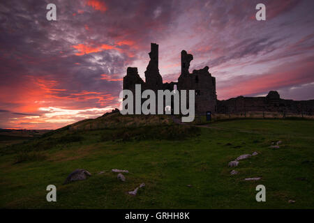 Die Vorahnung-Ruinen von Dunstanburgh Castle bei Sonnenuntergang an der Küste von Northumberland, England UK Stockfoto