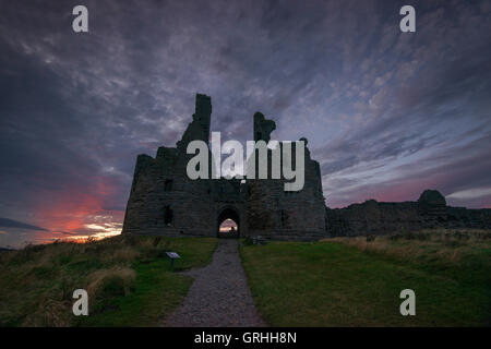 Die Vorahnung-Ruinen von Dunstanburgh Castle bei Sonnenuntergang an der Küste von Northumberland, England UK Stockfoto