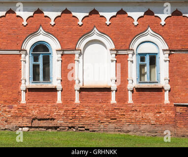 Roten Backsteinmauer mit Fenstern in weißen dekorativen Rahmen. Traditionellen alten russischen Architektur details Stockfoto