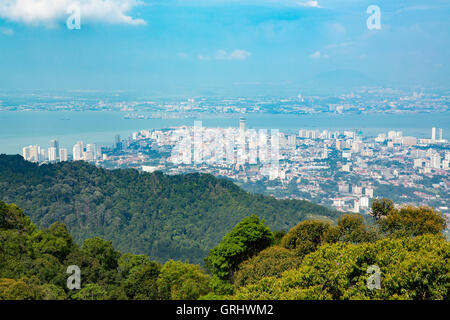 Blick auf Georgetown Penang aus Penang Hill. Helle Bäume im Vordergrund mit dunkleren Bäumen auf Hügel vor der Stadt. Stockfoto