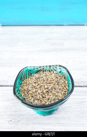 Samen von einem Mariendistel (Silybum Marianum) in einer grünen Schale auf rustikalen Tisch, Platz für Text. Stockfoto